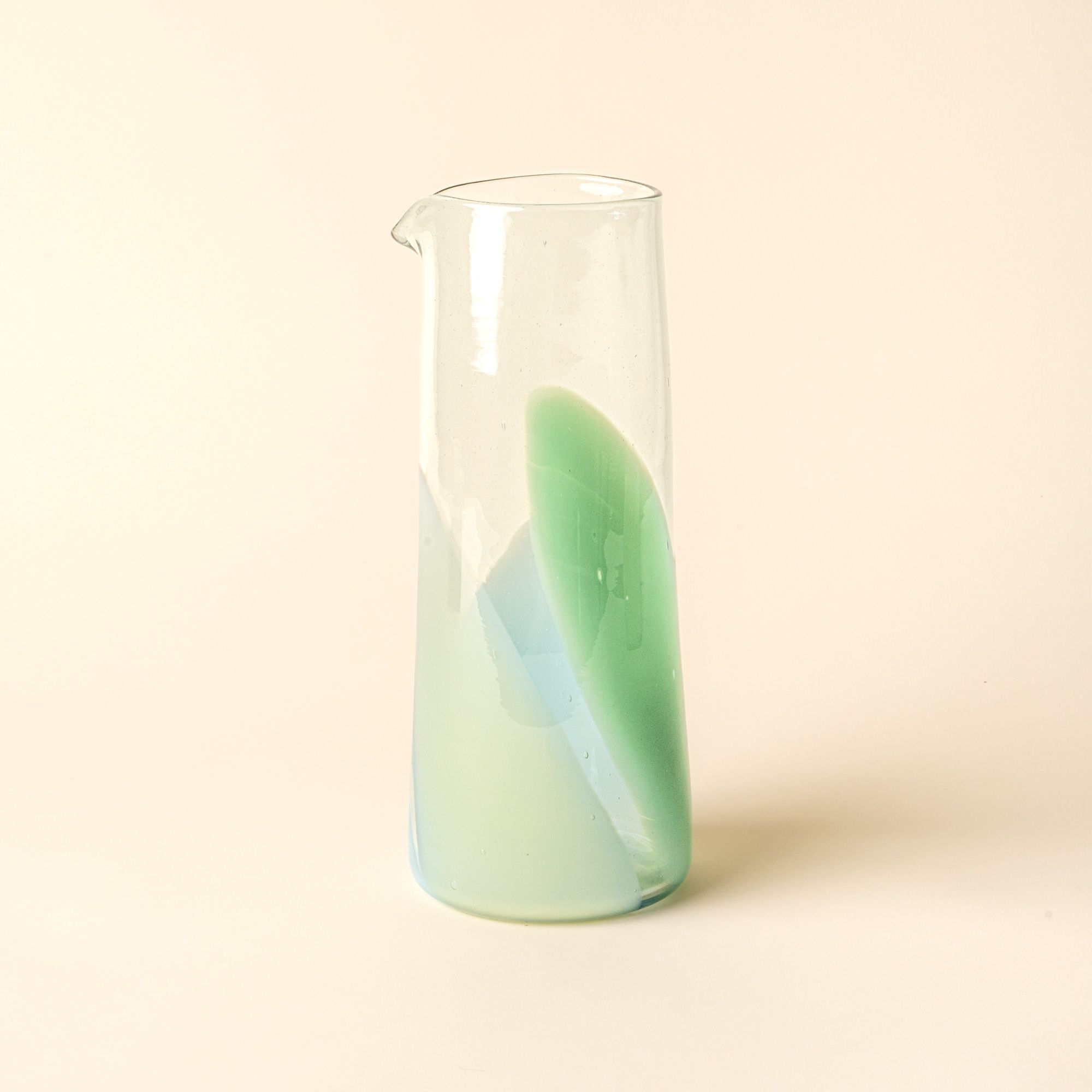 Simple glass pitcher featuring a soft pastel green swirl design, displayed against a neutral background.