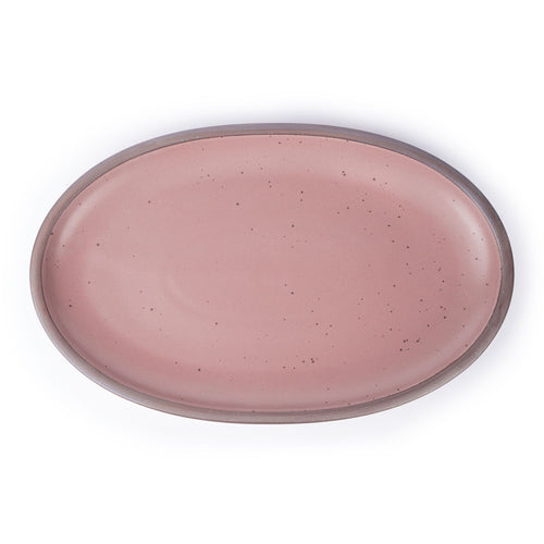 A large oval ceramic platter in a dusty mauve pink color featuring iron speckles and an unglazed rim