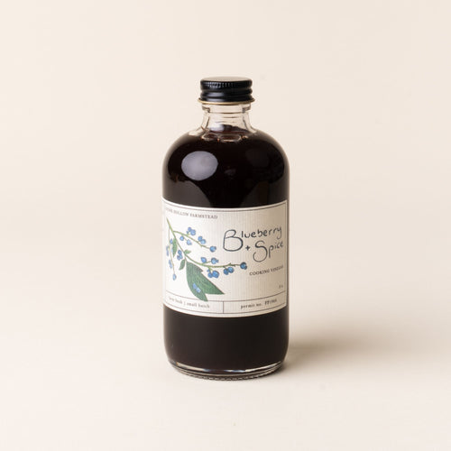 Bottle of Blueberry + Spice cooking vinegar, labeled with hand-drawn blueberry illustrations.