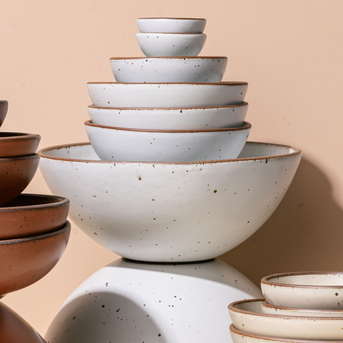 An artful stacking of ceramic bowls that range in sizes big to small and all in a cool white color.