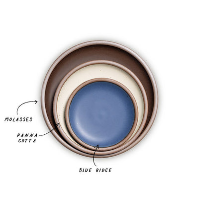A stack of 3 plates in Dinner, Side, and Cake sizes in a dark brown, warm off-white, and navy colors.