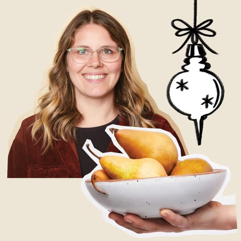 A woman with glasses smiling in front of a light background, holding a speckled ceramic bowl filled with pears. A whimsical illustration of an ornament hangs nearby.