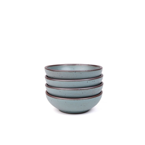 A stack of 4 small shallow ceramic bowls in a blue-grey color featuring iron speckles and an unglazed rim