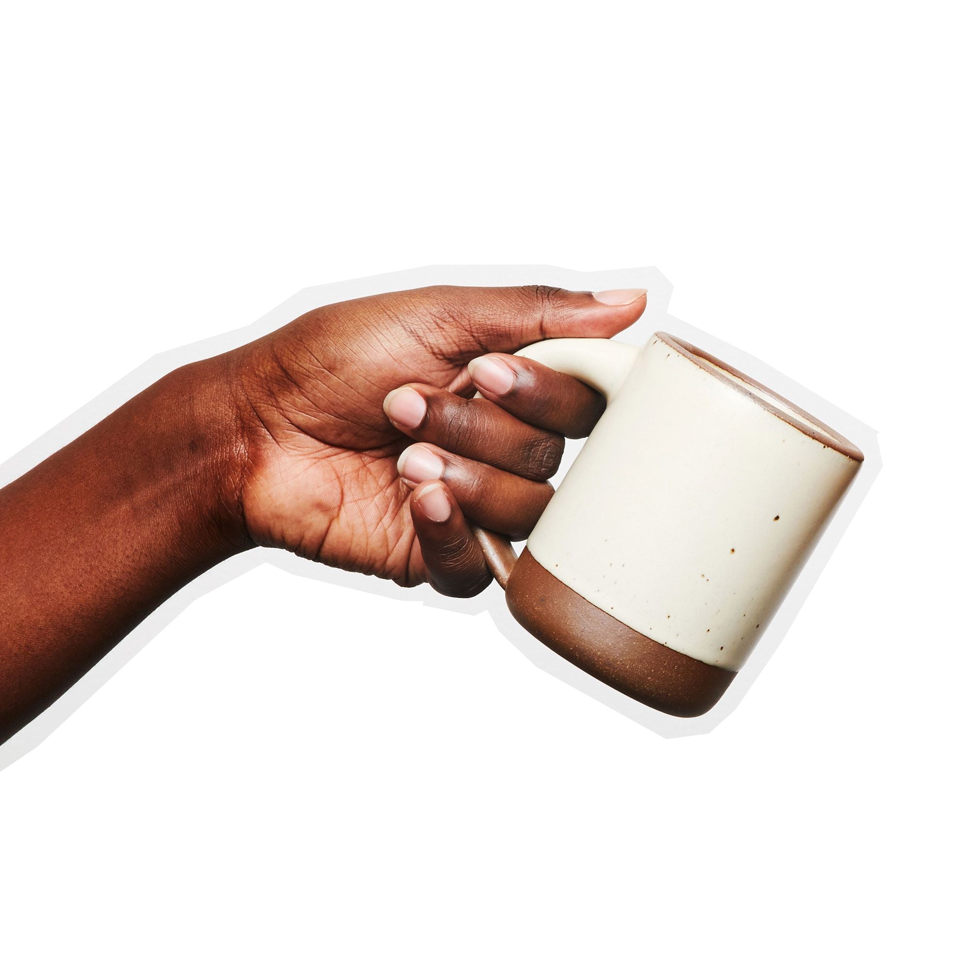 A hand holds The Mug in an off-white color with an unglazed rim and bottom