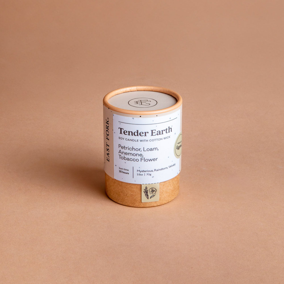 Small cardboard packaging tube with a candle inside with branding on it that says 'Tender Earth'