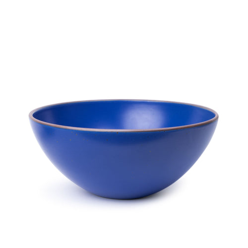 A large ceramic mixing bowl in a cobalt blue color featuring iron speckles and an unglazed rim