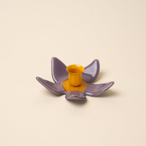 A sculptural glass purple flower candleholder with an orange center.