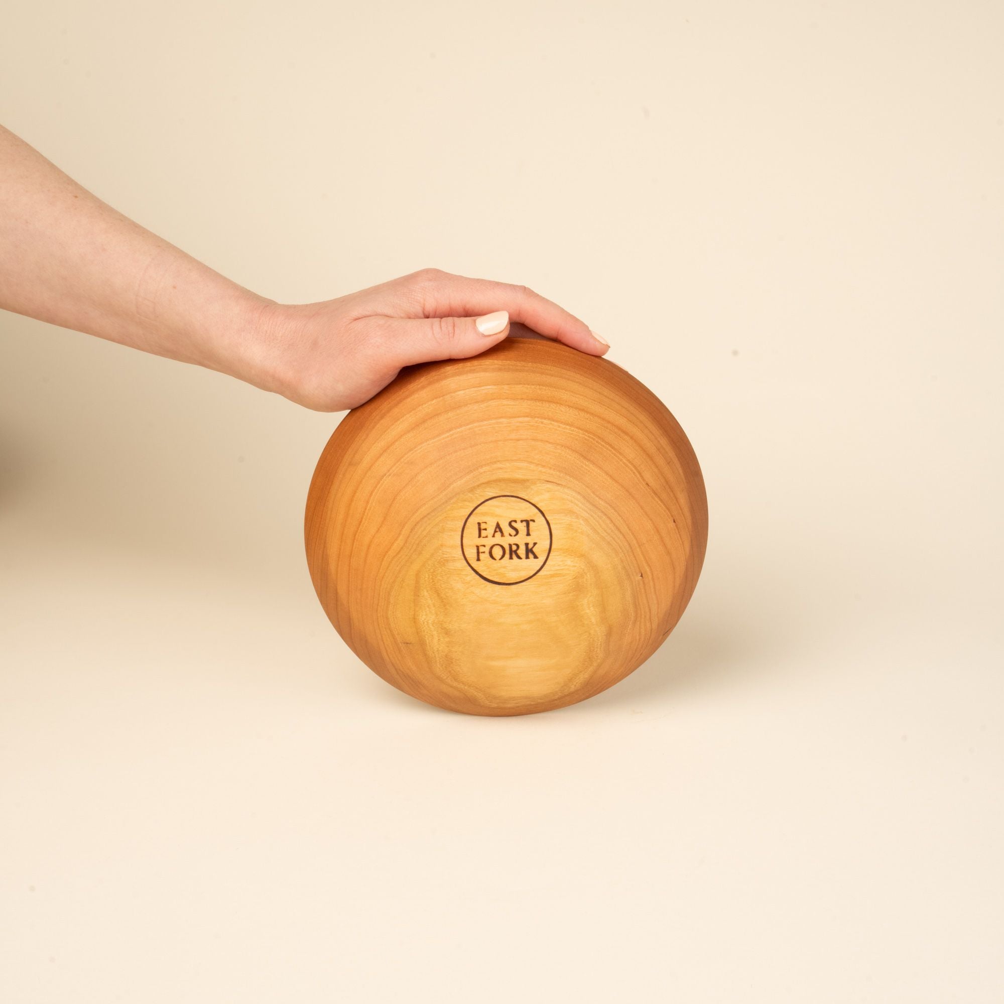 The bottom of a small cherry wood bowl with a stamp that reads "East Fork"