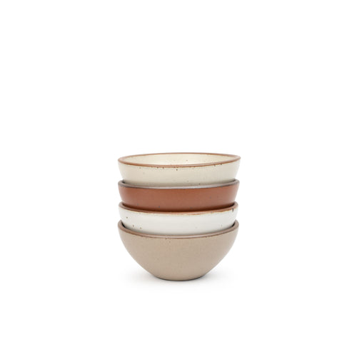 A stack of 4 small dessert sized rounded ceramic bowls in a cool terracotta, warm off-white, cool white, and warm pale brown colors featuring iron speckles and an unglazed rim