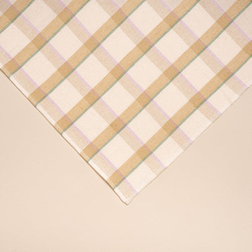 A closeup of A rectangular plaid placemat with lines of pastel pink, teal, and peach.