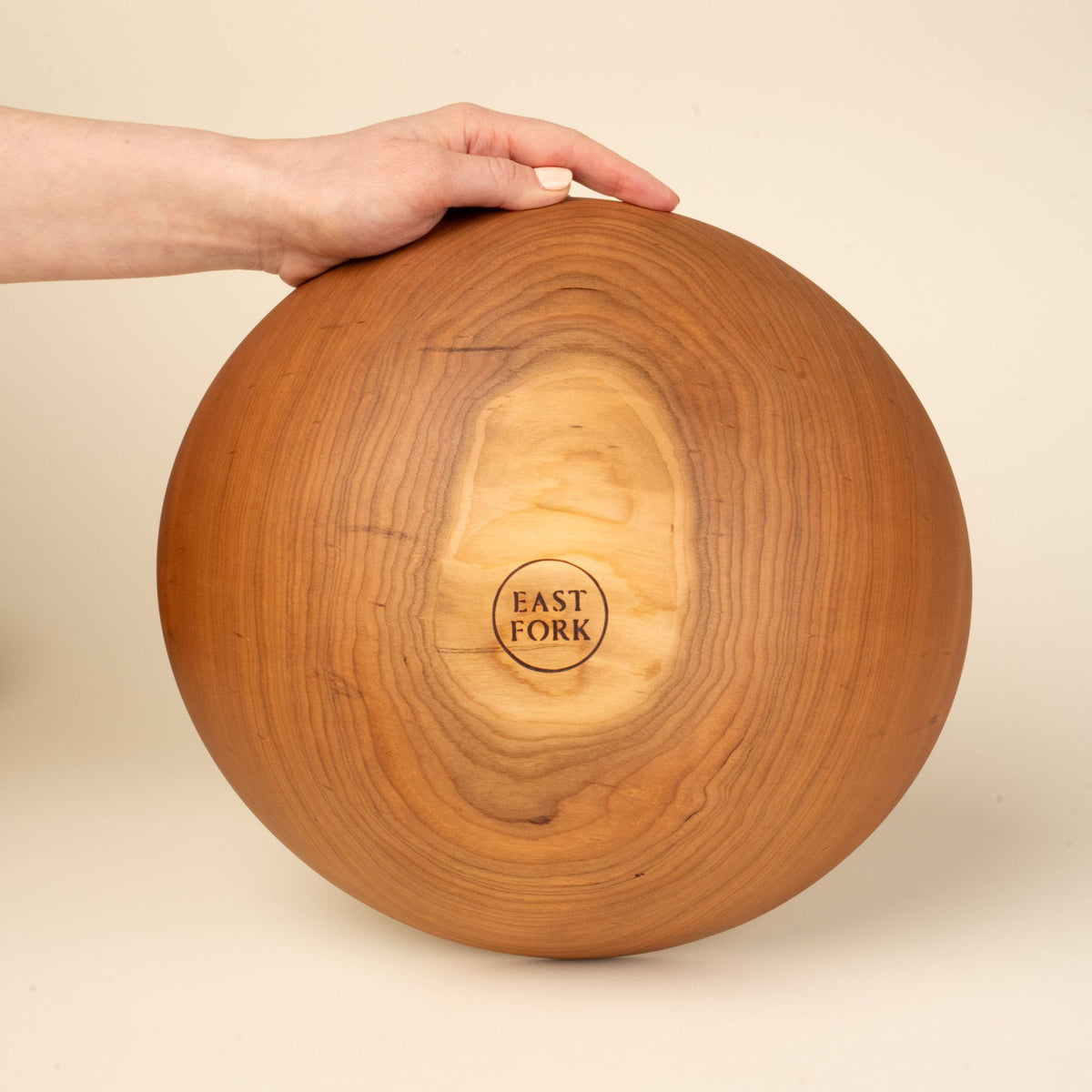 The bottom of a large cherry wood bowl with a stamp that reads "East Fork"