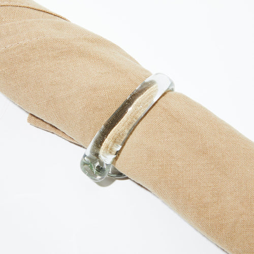 A glass napkin ring wrapped around a natural beige linen napkin