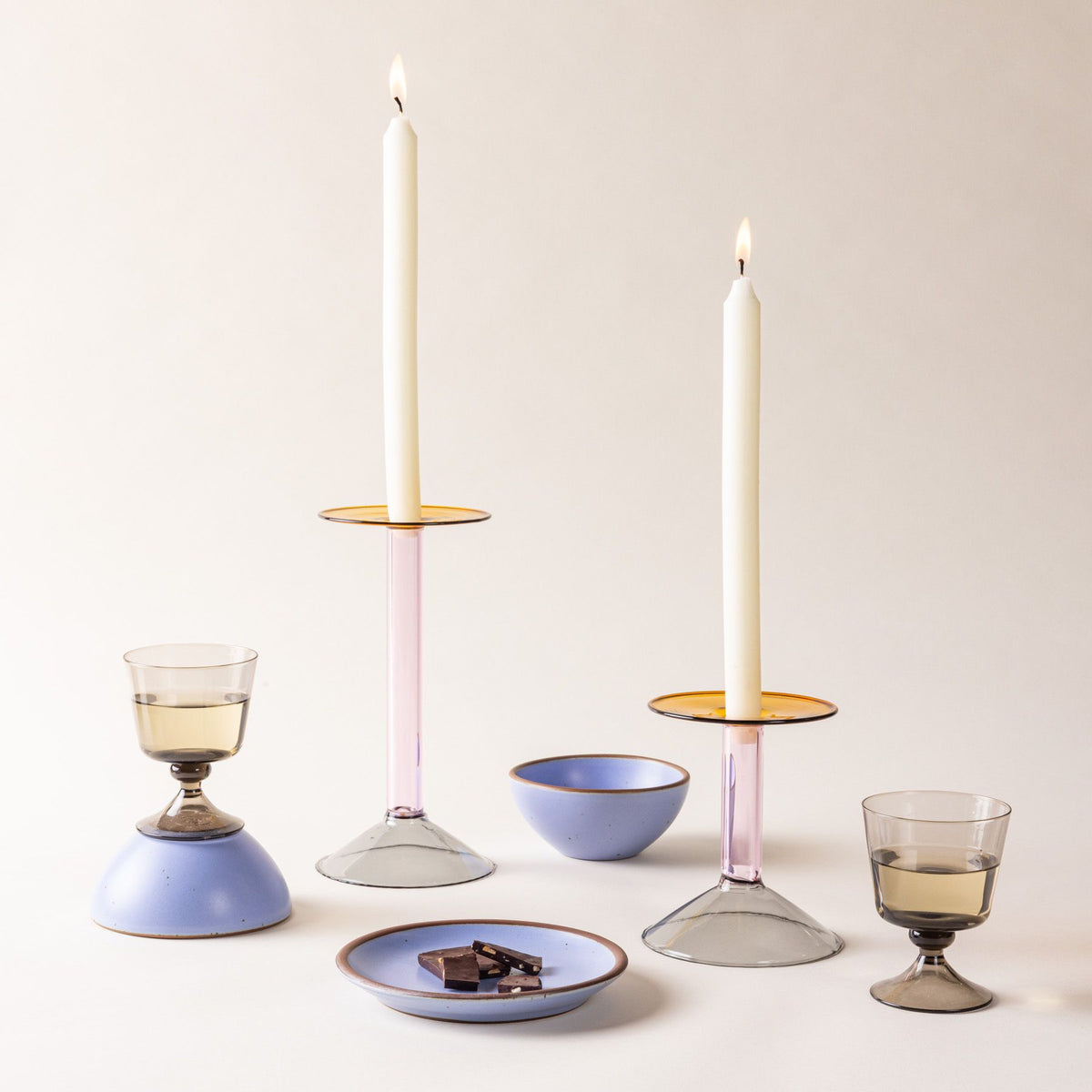 Colorful candle holders with white tapers, glasses of wine, and periwinkle dishes.