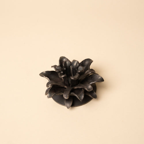 Black iron candle holder shaped like layered flower petals, shown empty on a neutral background.
