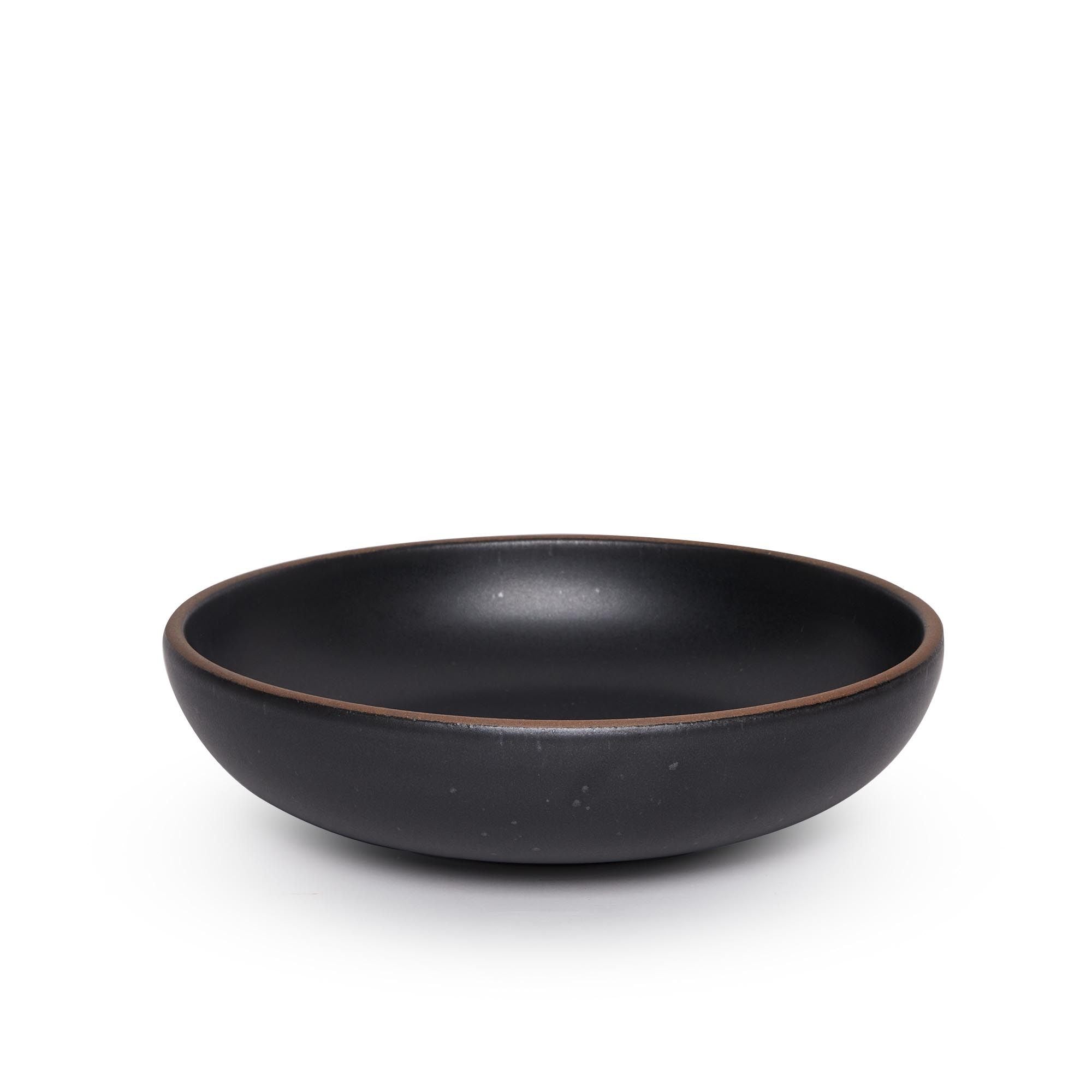 A large shallow serving ceramic bowl in a graphite black color featuring iron speckles and an unglazed rim