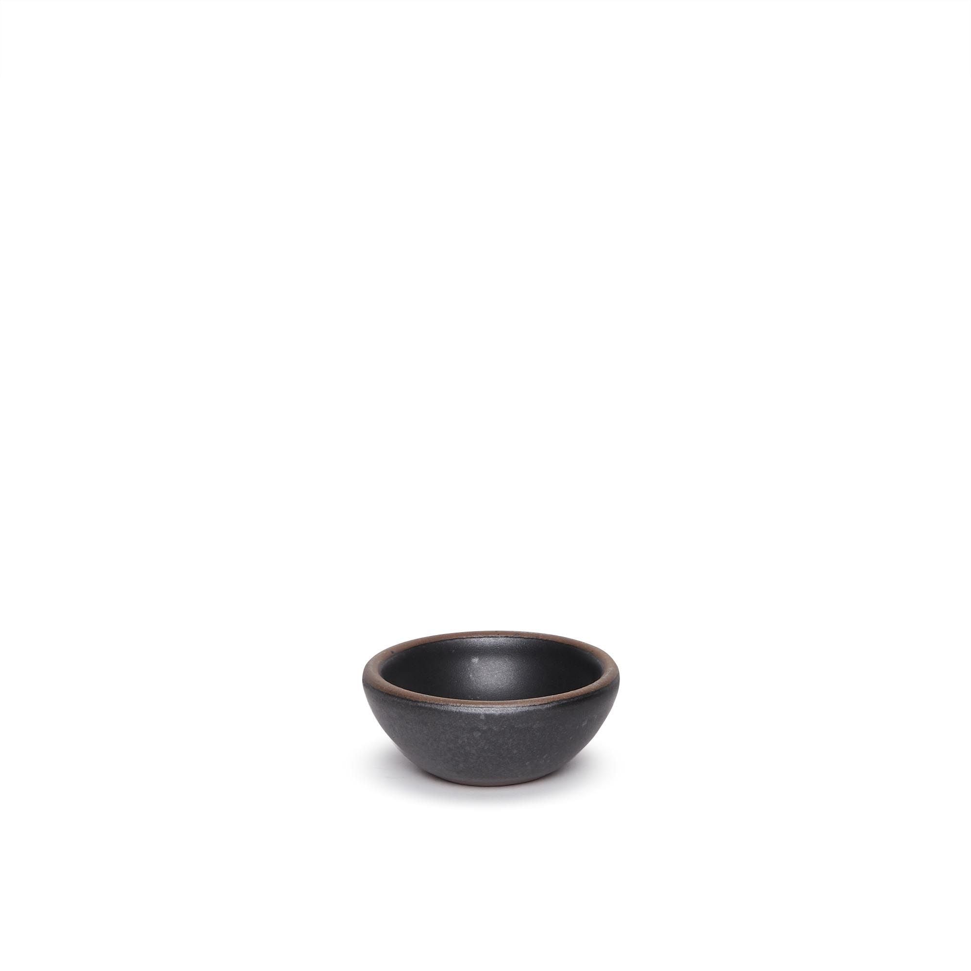 A tiny rounded ceramic bowl in a graphite black color featuring iron speckles and an unglazed rim