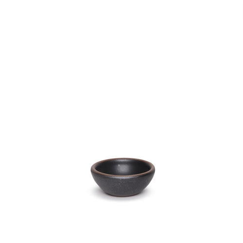 A tiny rounded ceramic bowl in a graphite black color featuring iron speckles and an unglazed rim