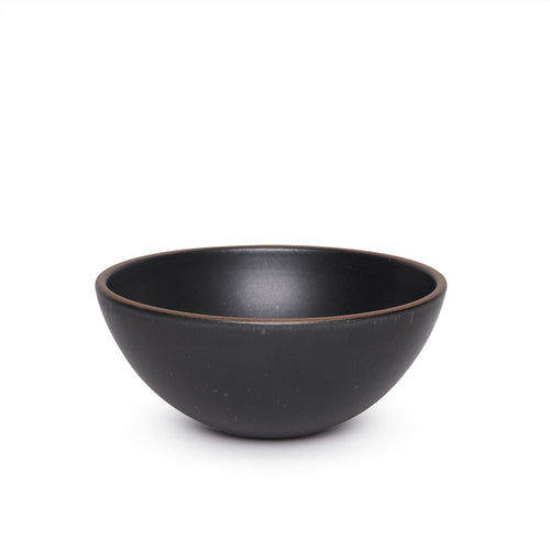 A large rounded ceramic bowl in a graphite black color featuring iron speckles and an unglazed rim
