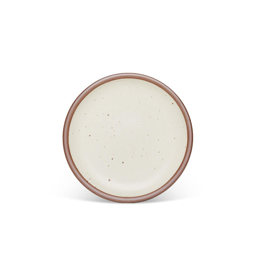 A medium sized ceramic plate in a warm, tan-toned, off-whitecolor featuring iron speckles and an unglazed rim.