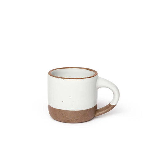A small sized ceramic mug with handle in an cool white glaze featuring iron speckles and unglazed rim and bottom base.