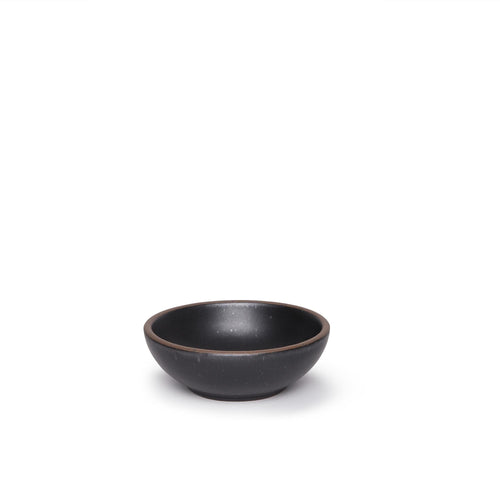 A small shallow ceramic bowl in a graphite black color featuring iron speckles and an unglazed rim