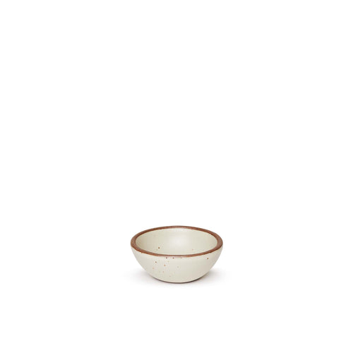 A tiny rounded ceramic bowl in a warm, tan-toned, off-white color featuring iron speckles and an unglazed rim