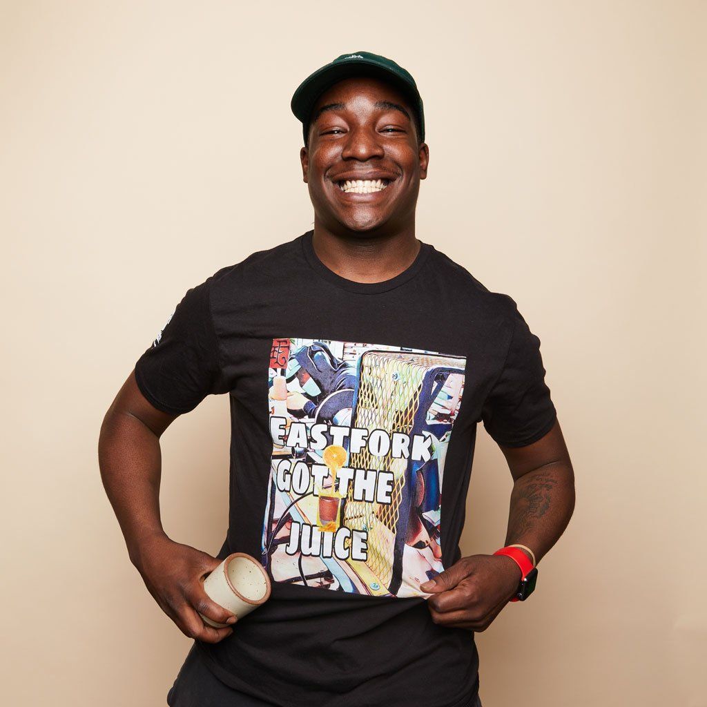A smiling person in a baseball hat wears a Drip Life "East Fork Got The Juice" tee.