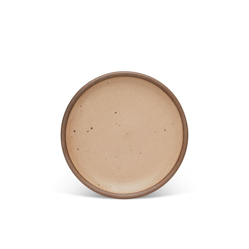 A medium sized ceramic plate in a pale warm brown color with iron speckles and an unglazed rim.