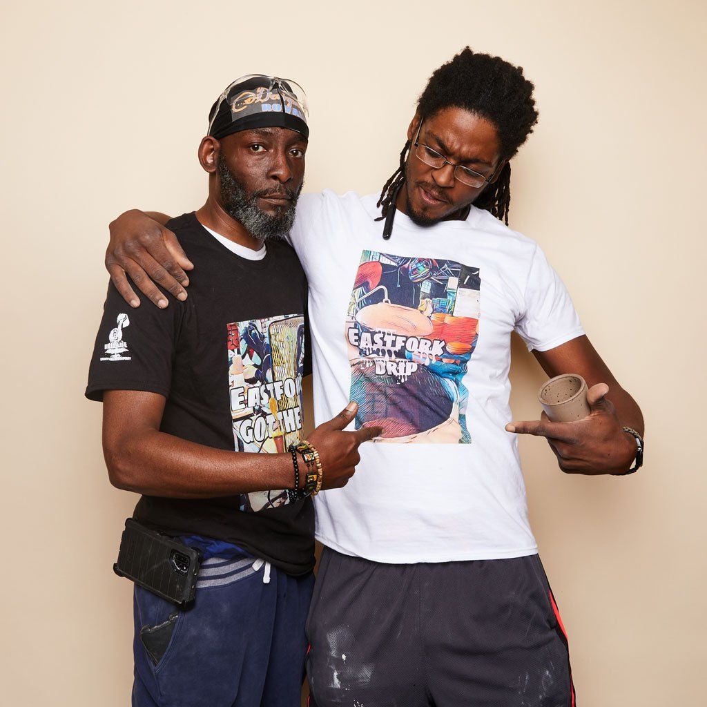 Two people each with an arm around the other's shoulder wearing Drip Life East Fork tees.
