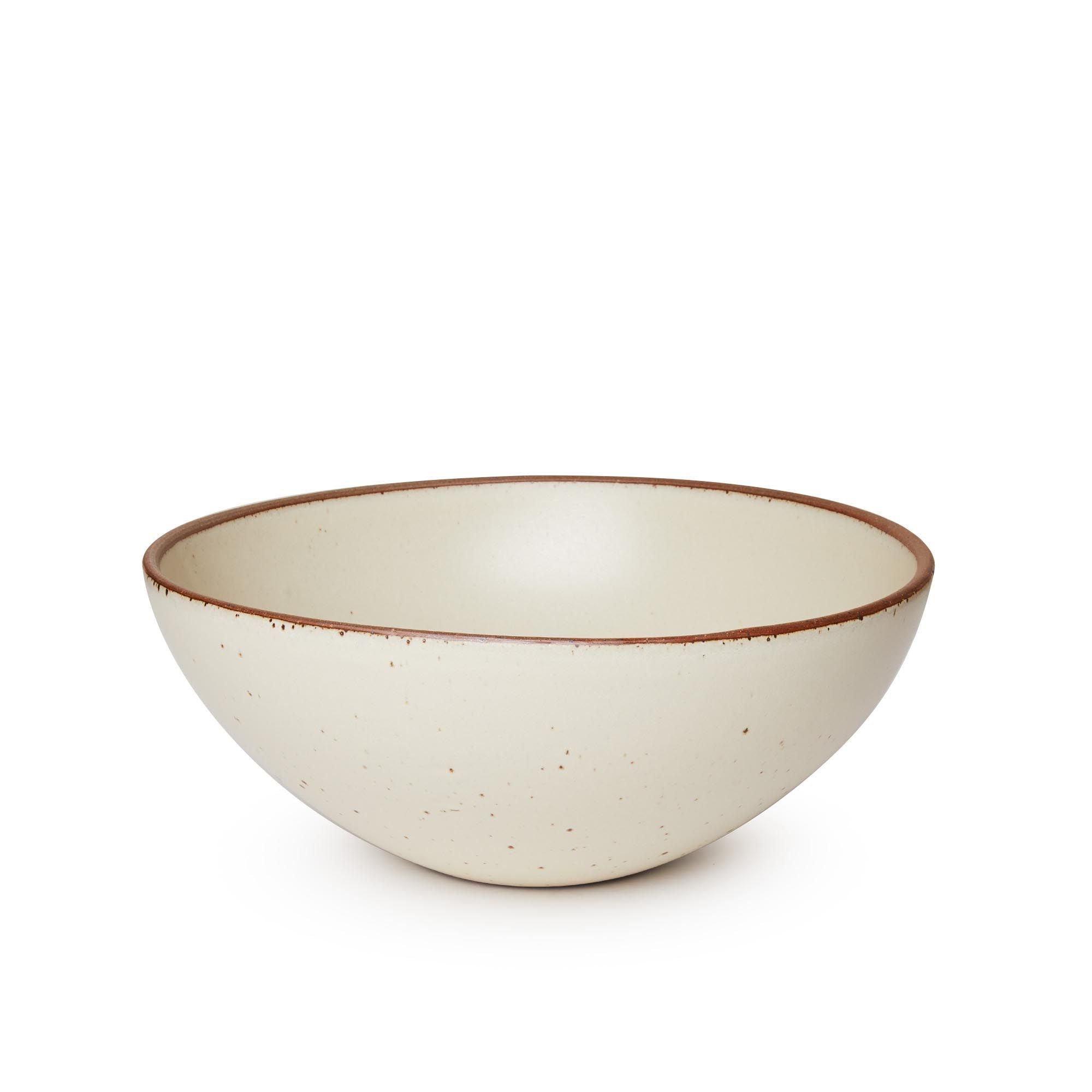 A large ceramic mixing bowl in a warm, tan-toned, off-white color featuring iron speckles and an unglazed rim