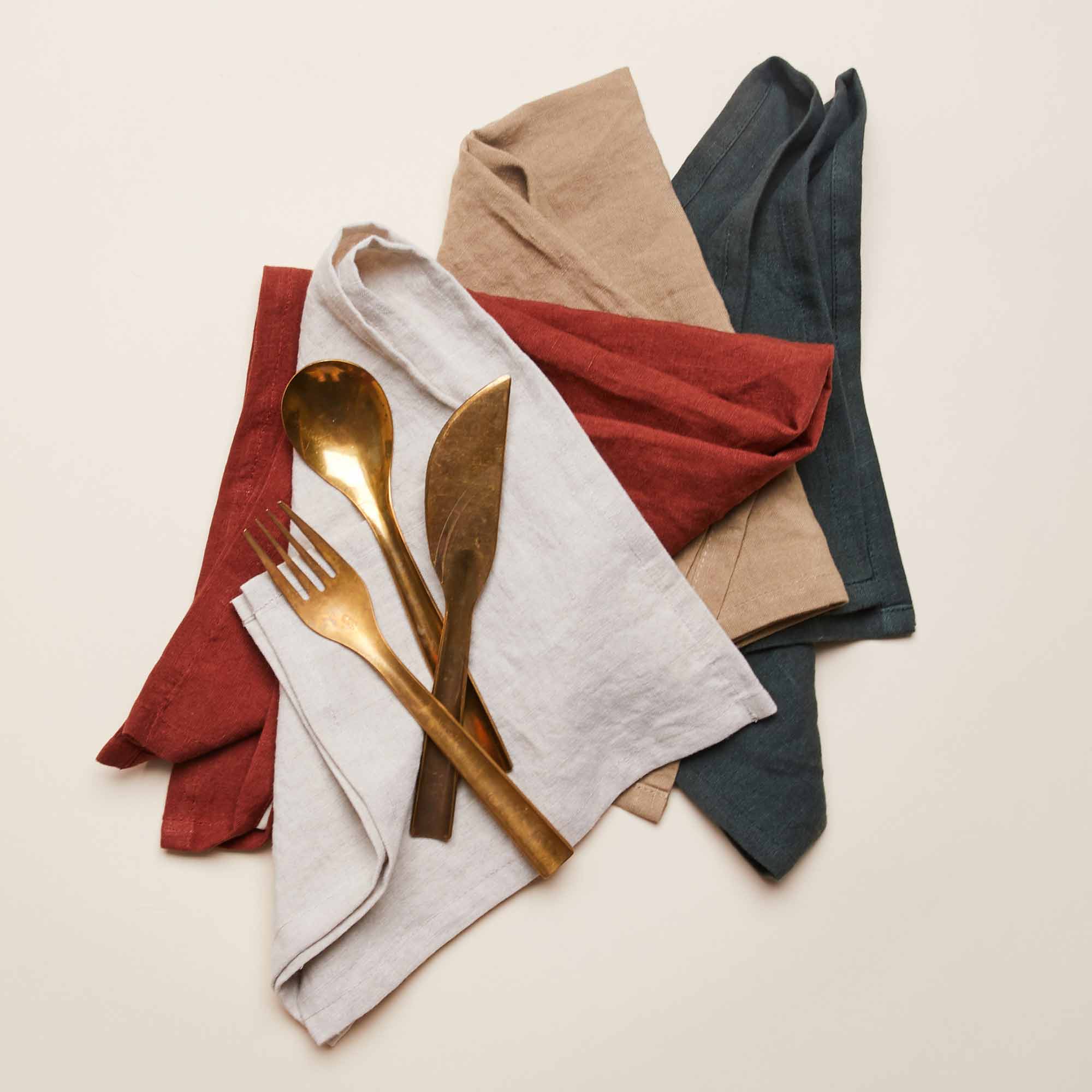 A brass fork, spoon and knife sit on top of four East Fork napkins