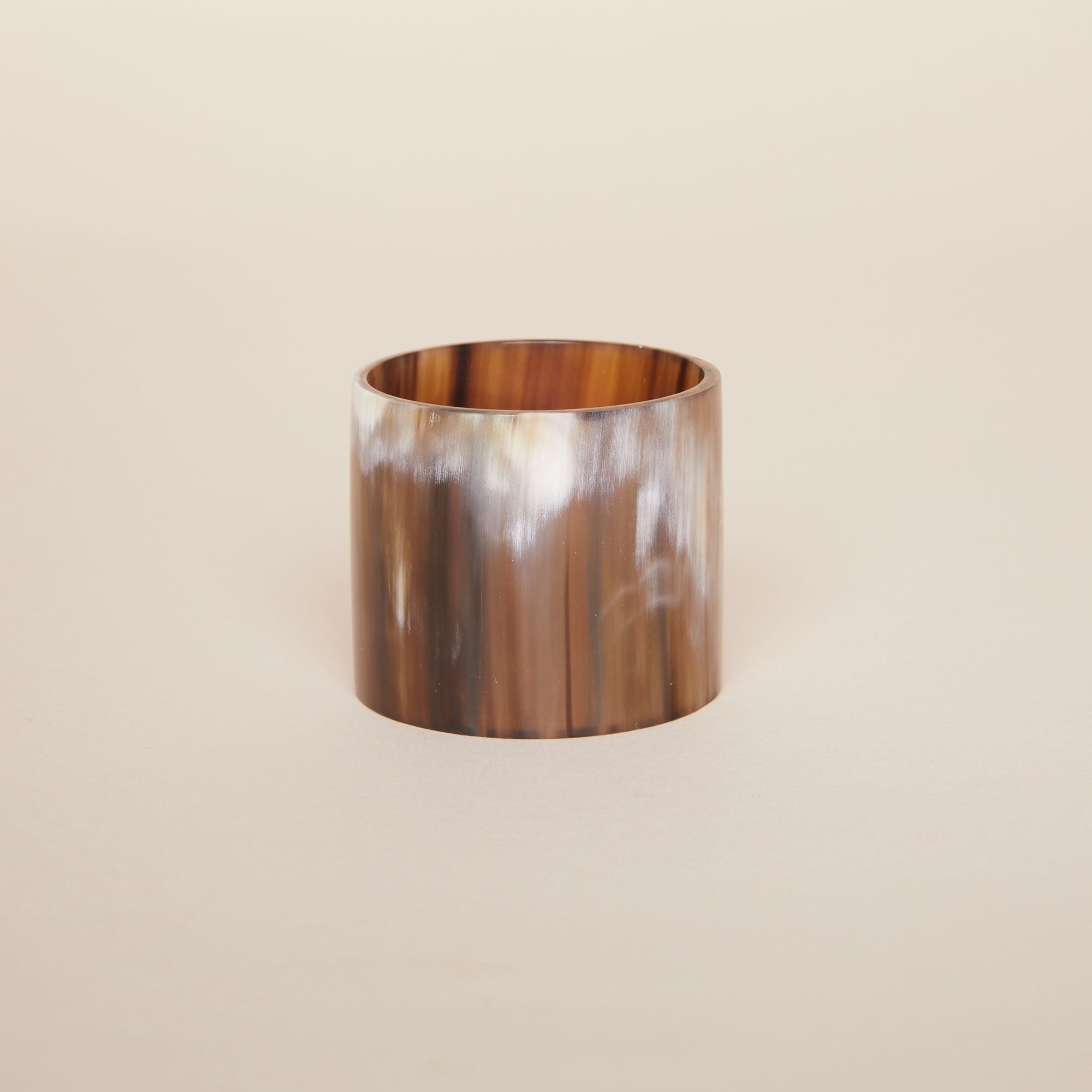 One cylindrical napkin holder with wavy vertical brown lines and accents in white