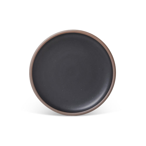 A dinner sized ceramic plate in a graphite black color featuring iron speckles and an unglazed rim.