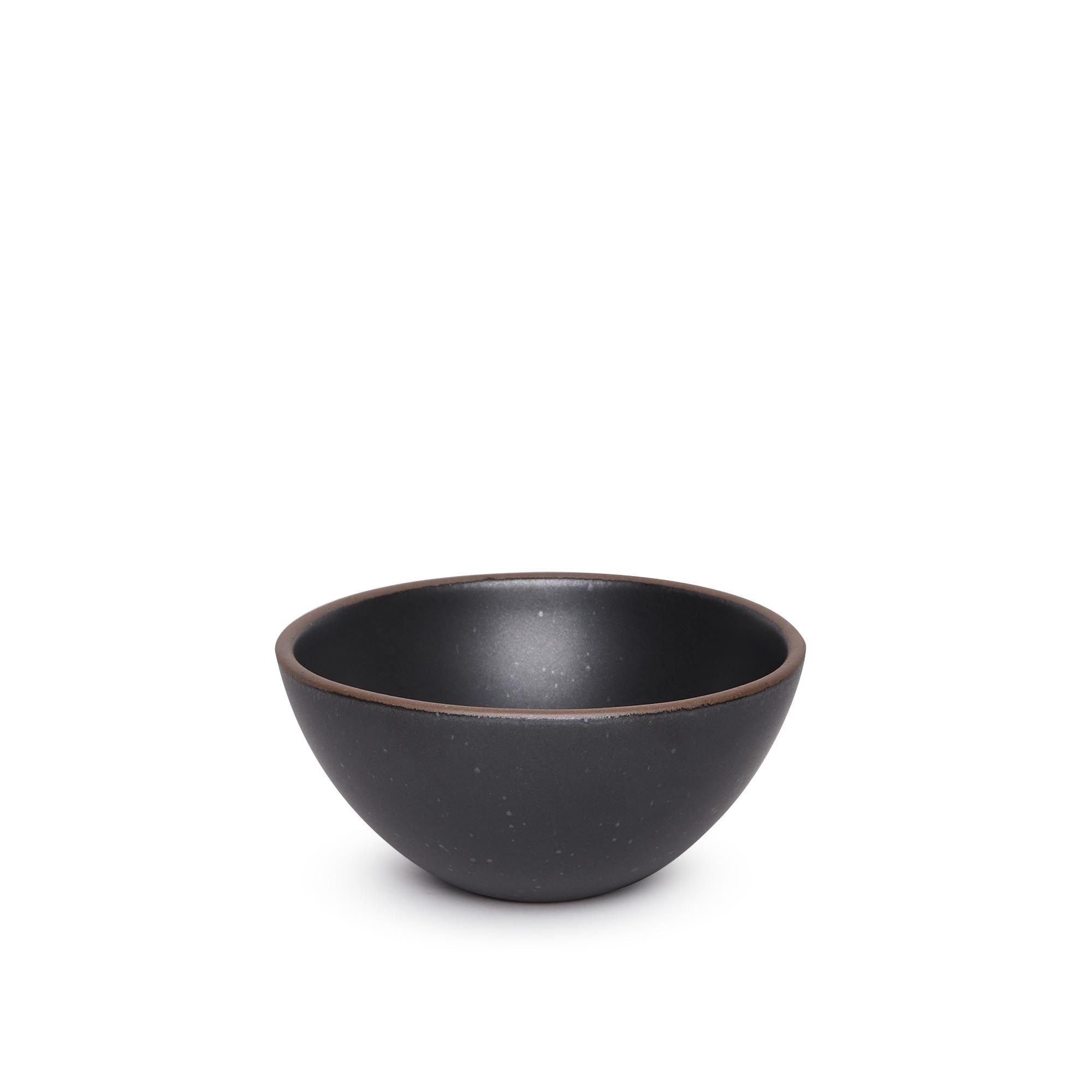 A medium rounded ceramic bowl in a graphite black color featuring iron speckles and an unglazed rim
