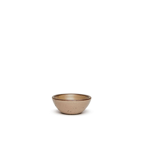 A tiny rounded ceramic bowl in a warm pale brown color featuring iron speckles and an unglazed rim