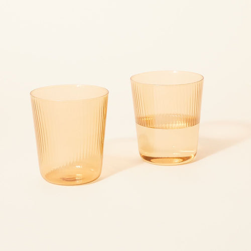 Two pale yellow clear glass vessels, one empty and the other half full of water