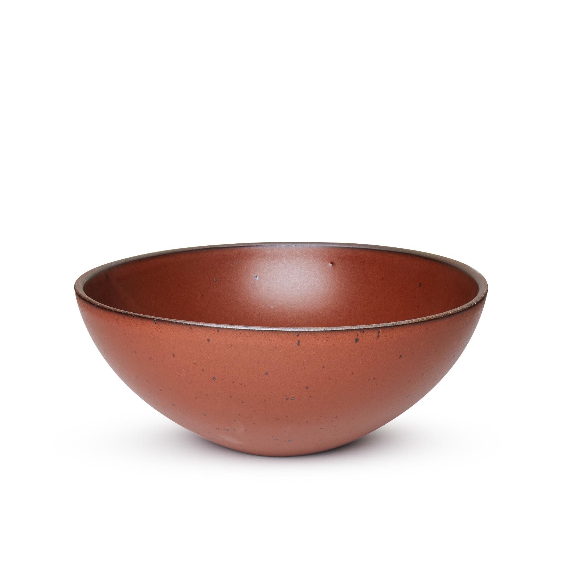 A large ceramic mixing bowl in a cool burnt terracotta color featuring iron speckles and an unglazed rim